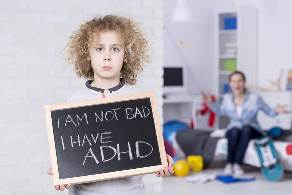Sad,Adhd,Boy,Holding,Small,Board,,Shouting,Mother,In,Background